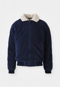 Marineblåt kordfløjlsjakke med en krave i cremefarvet faux fur, lynlås lukning og ribbetrøjer ved håndled og kant. Har sidelommer og en struktureret finish.