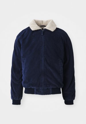 Navy corduroy jacket with a cream faux fur collar, zip closure, and ribbed cuffs and hem. Features side pockets and a textured finish.