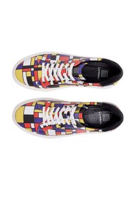 Colorful sneakers featuring a geometric pattern in red, yellow, black, and white, with white laces and a textured black interior.