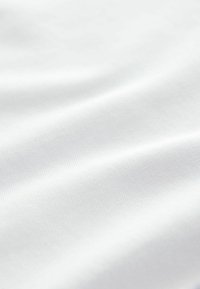 Uzumak bijele glatke tkanine s blagom teksturom i mekim naborima koji stvaraju nježne sjene i naglaske.