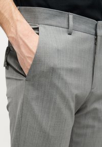Γκρι παντελόνι από υφή υφάσματος, με επίπεδη μπροστινή όψη, πλαϊνέ ς τσέπες και κομψή ζώνη μέσης.