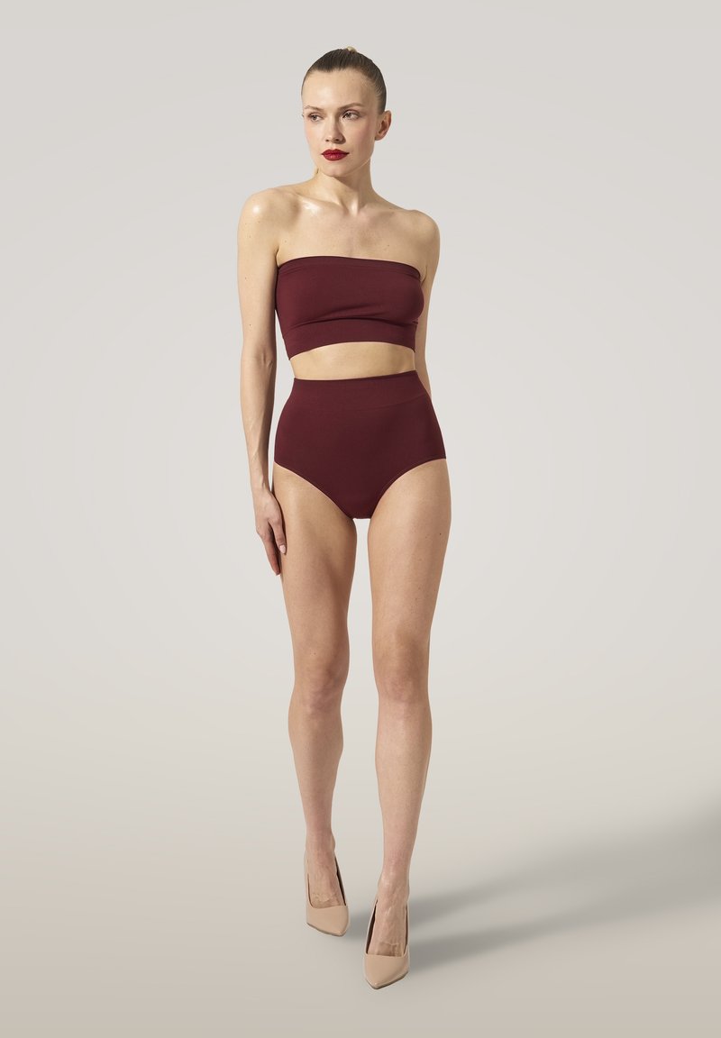 Bordeaux bandeau-top med höga bikini-bottoms, tillverkad av elastisk tyg. Modellen bär även nude högklackat på en neutral bakgrund.