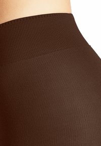 Leggings marroni a coste con una cintura liscia, che mostrano un motivo di tessuto texturizzato e un design aderente per comfort e flessibilità.