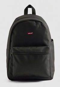 Rucsac din material textil negru, cu formă rotunjită, buzunar frontal cu fermoar și un mic logo Levi's roșu. Prezintă bretele căptușite pentru umeri și mâner superior.