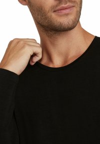 Black long-sleeve t-shirt with a round neckline, made of soft fabric. The design features a relaxed fit with a smooth texture.