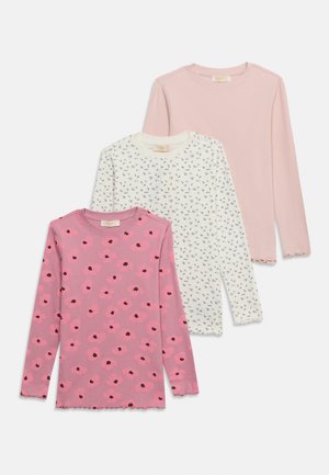 Drie meisjes tops met lange mouwen in roze met bloemenprint, crème met kleine zwarte bloemenprint en effen lichtroze, overlappend gerangschikt.