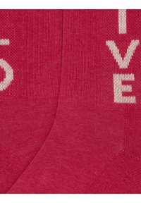 Calze rosse in tessuto lavorato a maglia con grande scritta bianca che recita "LIVE." Accentuate da una superficie liscia e un motivo coerente.