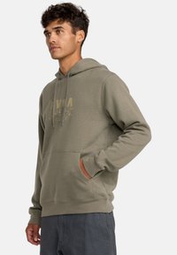 Olijfgroene hoodie van zacht materiaal, voorzien van een buidelzak, een capuchon met koord en een in gouden letters gedrukt logo op de voorkant.