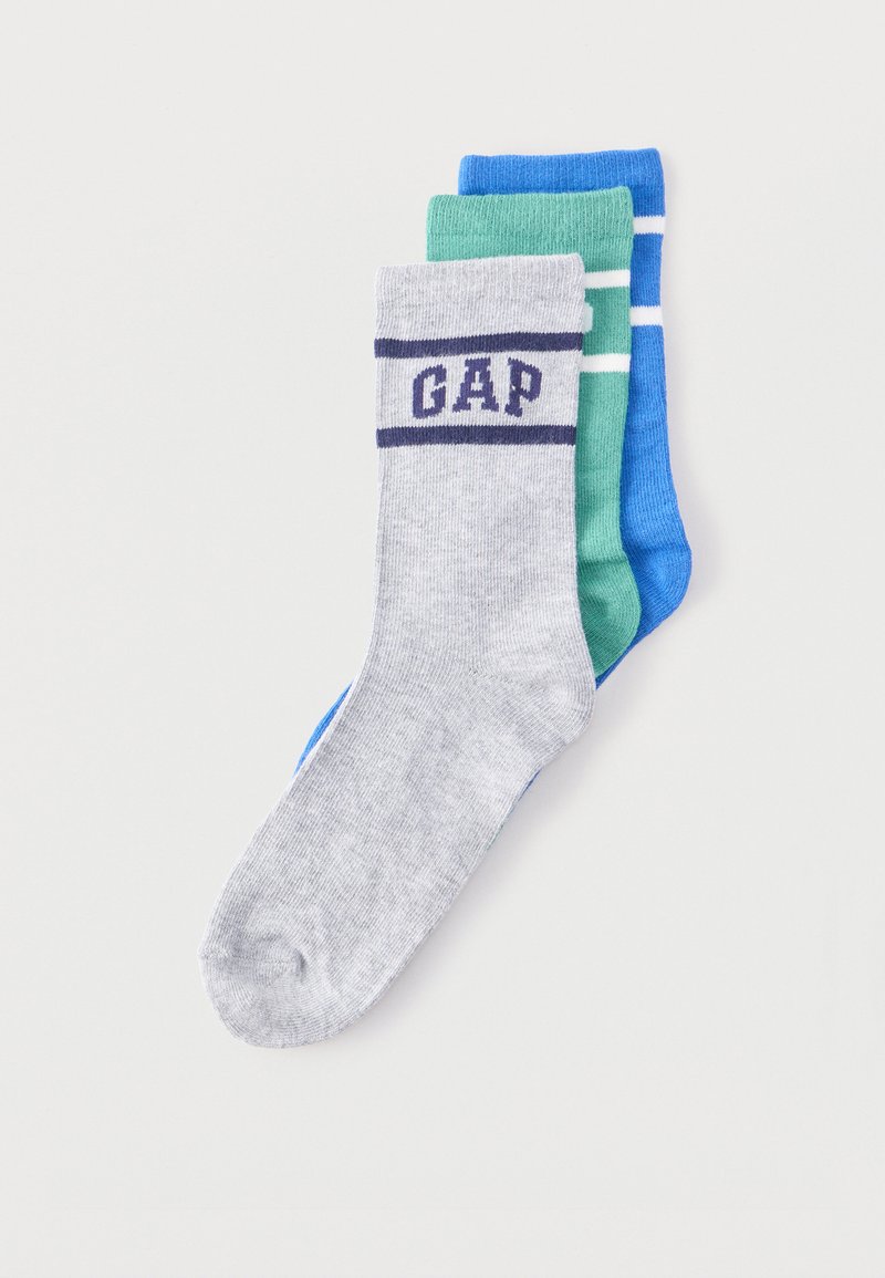 Τρία διπλωμένα πληρώματα κάλτσες σε γκρι, πράσινο και μπλε χρώμα· η γκρι κάλτσα εμφανίζει το λογότυπο "GAP" με ναυτικό μπλε ρίγες στο μανσέτο.