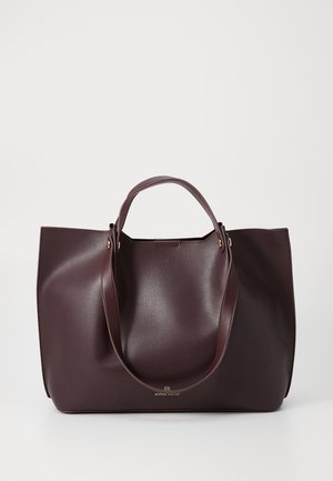 Burgundy leather tote bag with smooth texture, two sturdy handles, and a minimalist design. Features subtle gold hardware detail.