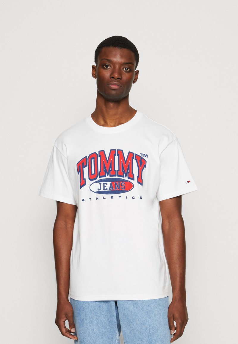 Tricou din bumbac alb cu un grafic îndrăzneț în roșu și albastru "TOMMY JEANS ATHLETICS" pe față. Guler standard și mâneci scurte.