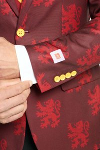 Bordoo bleiser, mille on punane lõvikuju, kollased nupud ja valged mansetid. Varrukal on "OPPO SUITS" silt, sile kangast tekstuur.