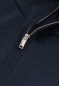 Marineblaue Zippullover aus Strickstoff. Verfügt über einen silbernen Reißverschluss mit einem rechteckigen Zipper, der eine glatte Textur und dezente Nähte zeigt.