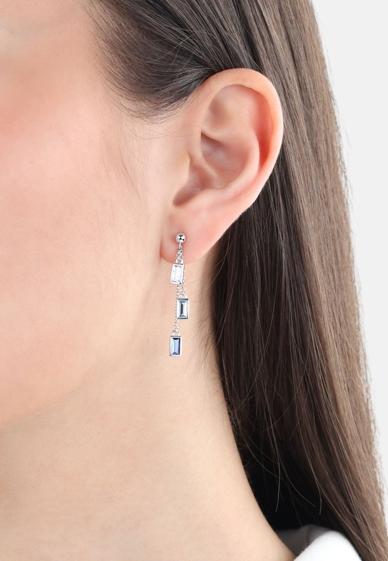 Pendientes de plata colgantes que presentan tres piedras preciosas rectangulares: una clara, una azul claro y una azul oscuro, suspendidas de una cadena delgada.