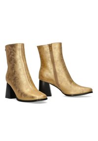 Botas de tobillo de imitación de cuero dorado con punta afilada, cremallera lateral y tacón alto grueso. Textura suave y acabado brillante y elegante.