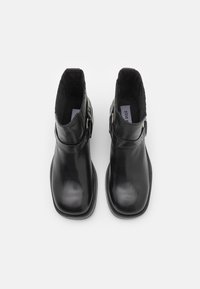 Black leather ankle boots with a smooth texture, round toe, and buckle accent on the side. The interior features a soft lining.