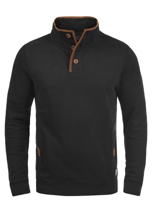 Čierny sveter s vysokým golierom a tromi hnedými gombíkmi. Obsahuje hnedé akcenty okolo goliera a bočných vreciek. Vyrobený z mäkkej tkaniny.