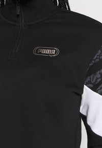 Sudadera deportiva negra con cuello alto y media cremallera. Presenta el logo de Puma en plateado en el pecho y detalles con patrón en las mangas.