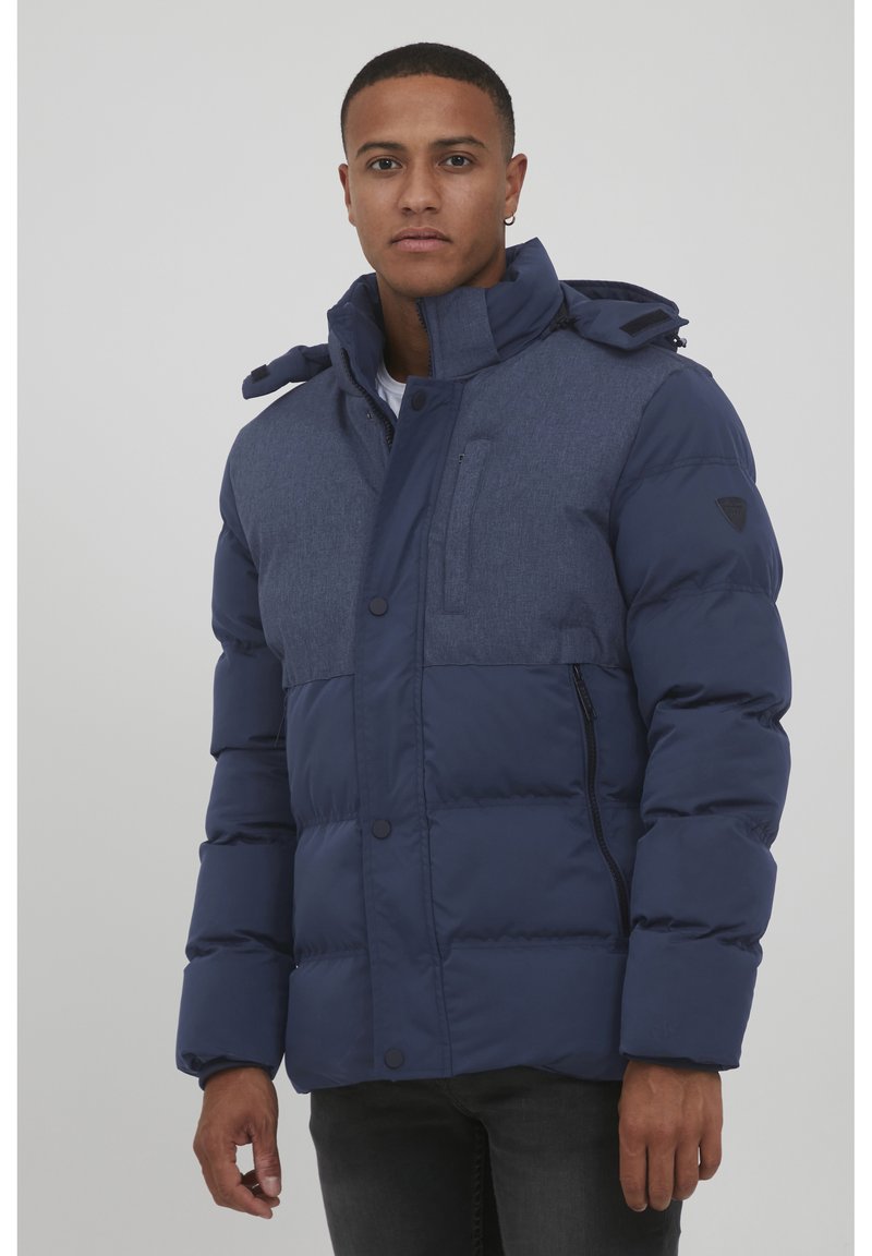 Navy blue puffer jacket with a blended fabric upper, high collar, zip pockets, and buttons, featuring a hood with adjustable toggles.
