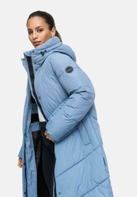 Cappotto lungo, leggero e blu chiaro imbottito con cappuccio, caratterizzato da motivi a rombi, bottoni a pressione e un'etichetta con logo sulla manica.