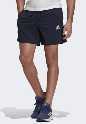 Pantalones cortos deportivos de color azul marino, confeccionados con tela ligera, que cuentan con una banda elástica en la cintura con cordón y un logo blanco de Adidas en el lado izquierdo.
