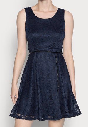 Robe sans manches en dentelle bleu foncé avec un décolleté rond, une taille cintrée avec une fine ceinture noire et une jupe évasée au-dessus du genou.