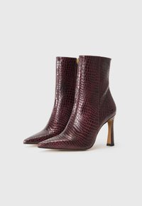 Stivaletti bordeaux con motivo coccodrillo, punta affusolata e tacco a stiletto. Presentano una zip laterale per una facile indossabilità.