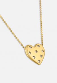Ciondolo a forma di cuore in oro con piccole aperture a forma di cuore, caratterizzato da una finitura lucida e attaccato a una catena di perline.