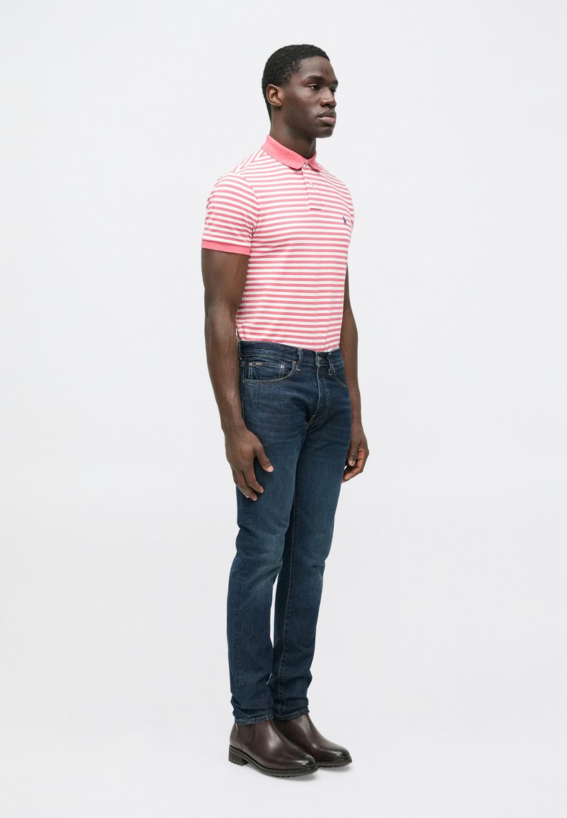 Red and white striped polo shirt with a collar, paired with dark blue denim jeans and brown leather ankle boots.