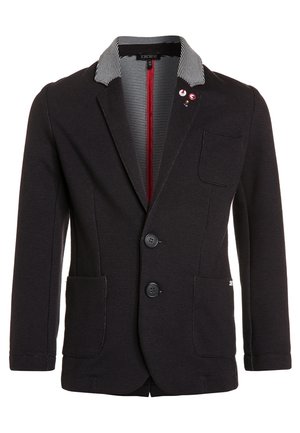 Schwarzer Blazer mit strukturierter Oberfläche, gestreiftem Innenkragen, zwei vorderen Knöpfen, drei aufgesetzten Taschen und drei bunten Anstecknadeln auf der linken Seite.