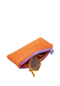 Pomarańczowe etui na okulary z tkaniny z fioletowym suwakem, mieszczące sześciokątne brązowe okulary przeciwsłoneczne. Wyróżniające się wytłoczone logo na powierzchni etui.