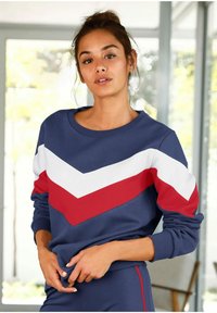 Sudadera azul marino con rayas en forma de chevron en blanco y rojo. Cuenta con un escote redondo y puños acanalados. Tejido suave con un corte relajado.