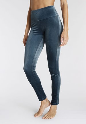 Blue velvet leggings feature a high waistband, smooth texture, and a fitted design, extending to the ankle with side seam detailing.