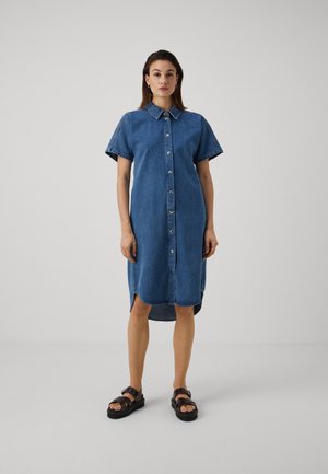 Denim shirt dress with short sleeves, front buttons, and side slits. Features a classic collar and a relaxed fit. Blue color. Flat sandals.