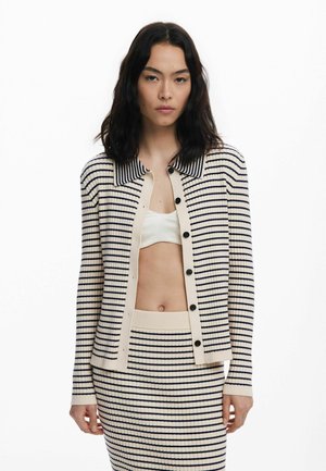 Cream cardigan with navy stripes, ribbed texture, and a collared neckline. Features front buttons and matching striped skirt.