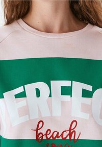Sudadera de color rosa claro y verde con el texto "PERFECT" en blanco y en negrita; corte casual; tejido suave; cuenta con un cuello redondo; ideal para usar en la playa.