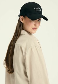 Czarna czapka baseballowa z haftem "LONDON TENNIS CLUB" w kolorze białym. Posiada zakrzywiony daszek i regulowany pasek z tyłu.