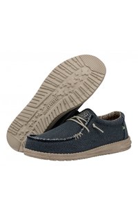 Chaussures en tissu bleu tressé avec semelles en caoutchouc beige, présentant un design à lacets et des accents cousus. Motif intérieur texturé visible.