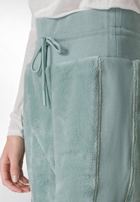 Bløde teal joggers med en blød tekstur, der har en ribbet talje, snøre og kontrasterende sidelommer for ekstra detaljer.