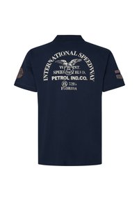 Mörkblå polo skjorta med krage, med vit tryckt text och en örn-design på baksidan. Inkluderar ärmfläckar för detaljer.