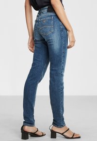 Bledé modré džíny s rovný fit, mají zadní kapsy a vysoký pas, v kombinaci s černými sandály na blokovém podpatku se stahovacími pásky.