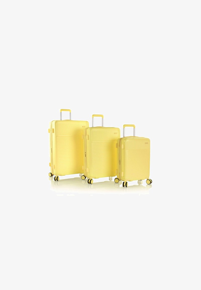 Tre valigie rigide gialle con texture a righe, manici estensibili e ruote girevoli. Varie dimensioni, da grande a piccola.