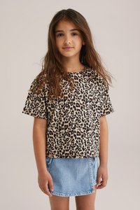 Beige un melnu leoparda rakstu krekli ar īsām piedurknēm, apvienots ar gaiši zilu denim svārku. Ikdienas piegriezums ar apaļu kakla izgriezumu.