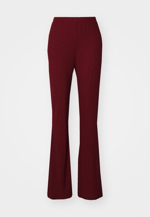 Burgundy ribbed flared pants with an elastic waistband. Features a smooth texture and a fitted silhouette extending to a flared hem.