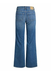 Sinised volangidega teksapüksid kõrge vöökohaga, tagaküljel kaks taskut ja pruun nahast silt. Sile tekstuur ja keskmise pleegitusega.