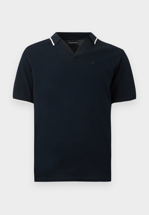 Granatowa koszulka polo z krótkim rękawem, białe wykończenia na kołnierzyku i rękawach, dekolt w kształcie litery V oraz subtelne logo na piersi.