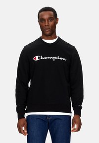 Felpa nera a girocollo realizzata in cotone, con un grande logo "Champion" ricamato in bianco e rosso sul petto.