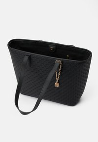 Black tote bag with textured fabric, featuring a smooth finish, two shoulder straps, and a gold-toned charm detail on the side.