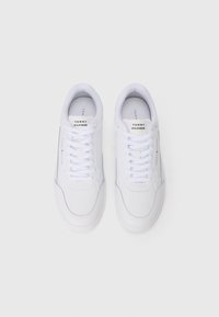 White sneakers made of smooth leather with flat laces, round toe, and subtle branding on the tongue and side.