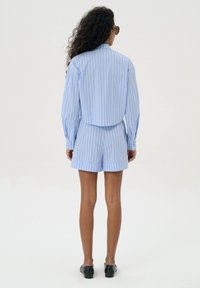 Lichtblauwe gestreepte shirt en shorts, slim fit stijl, lange mouwen, knoopmanchetten, zachte textuur, gecombineerd met zwarte instappers.